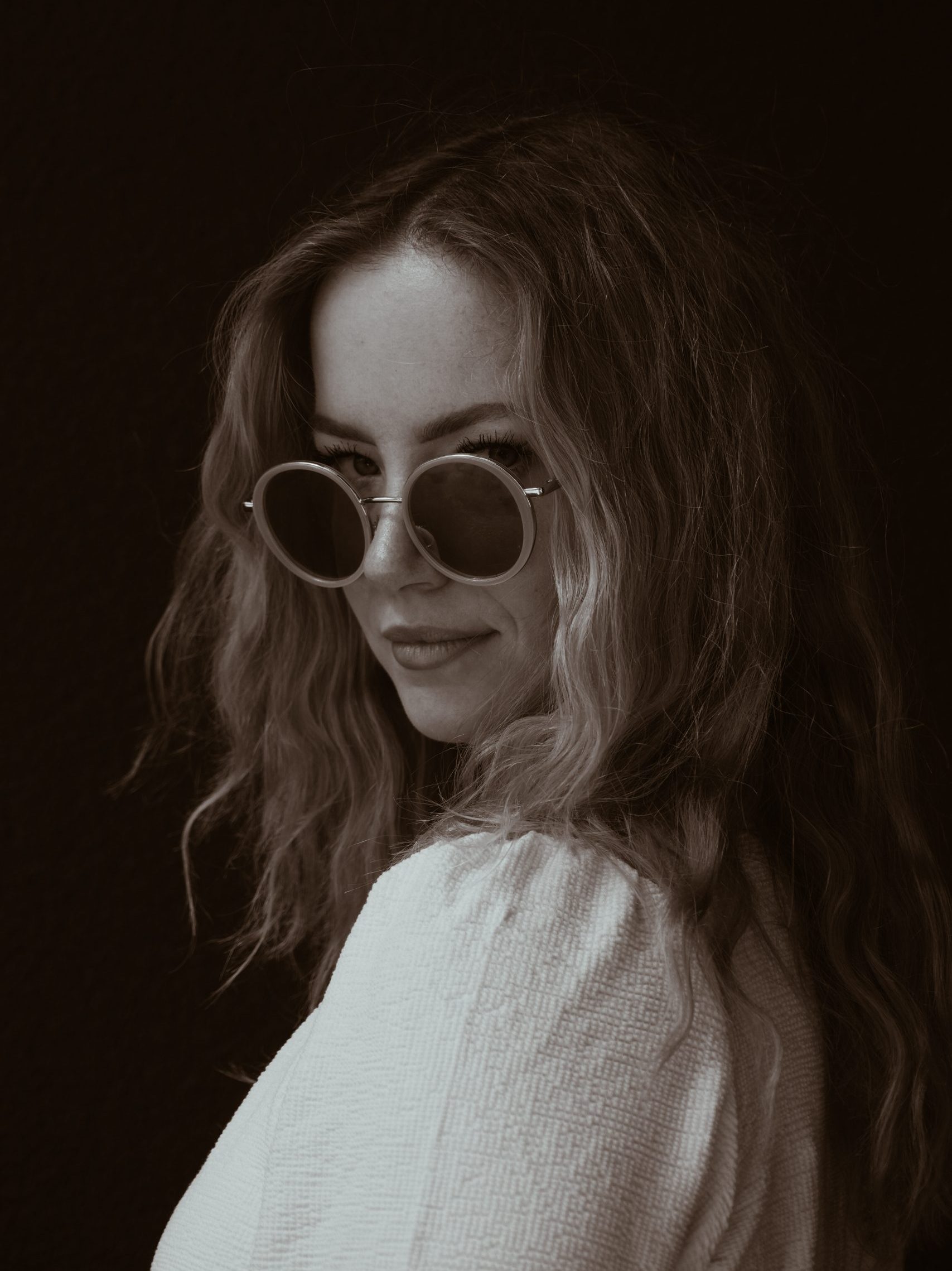 Portrait einer jungen blonden Dame mit Sonnenbrille in Sepia